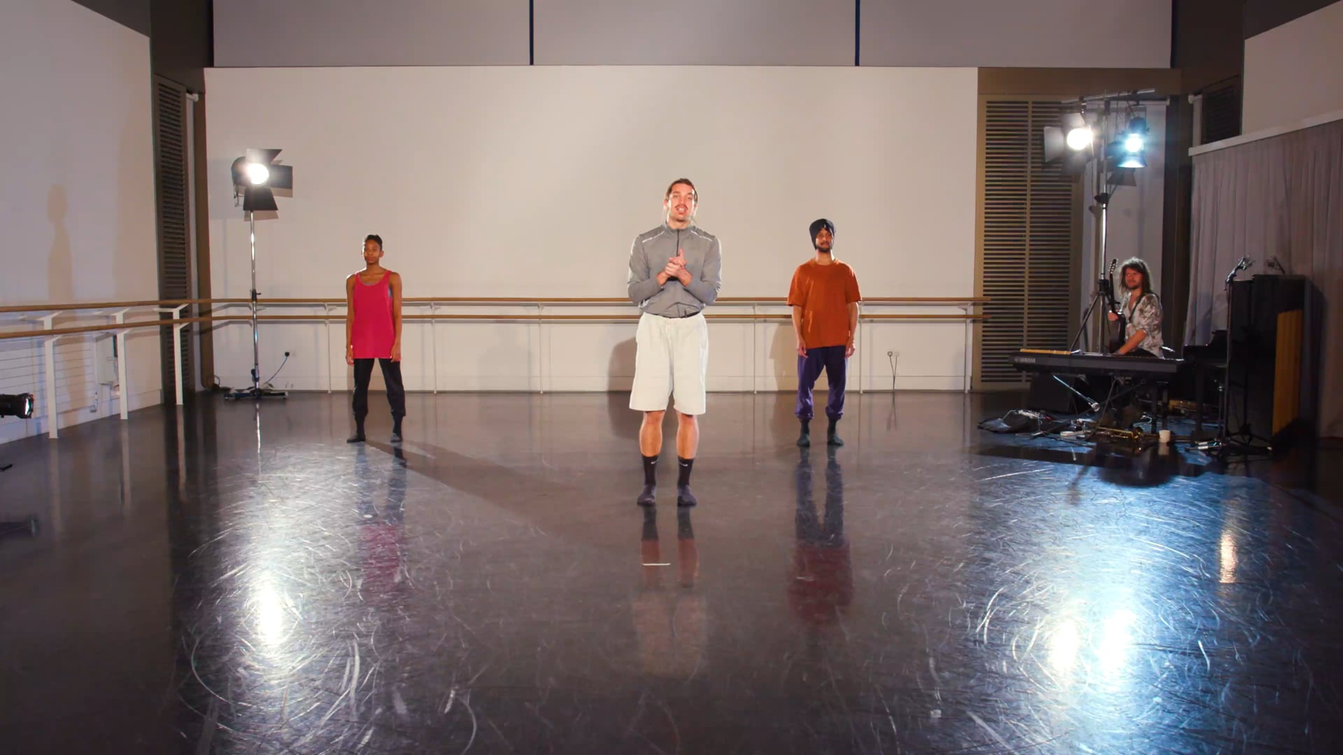 a group of people standing around a dance studio.