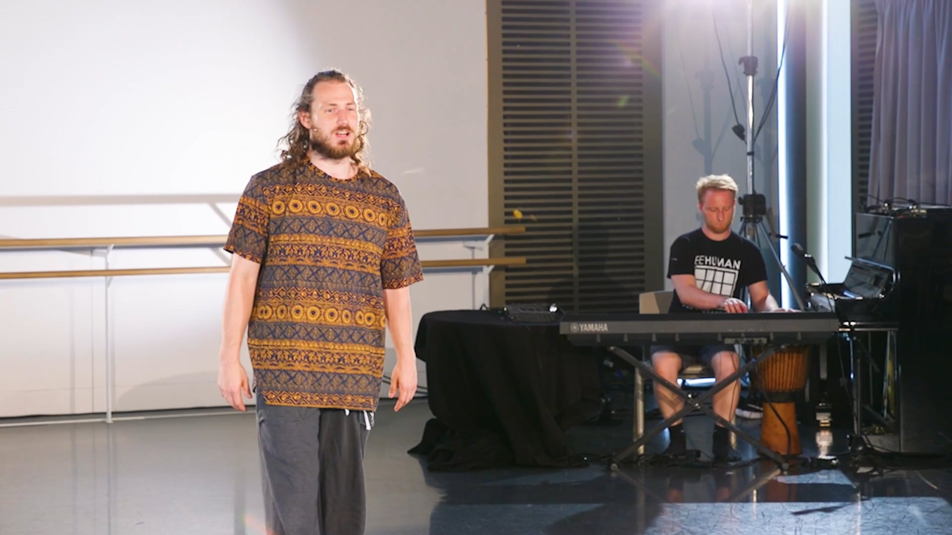 a man standing in front of a piano in a room.