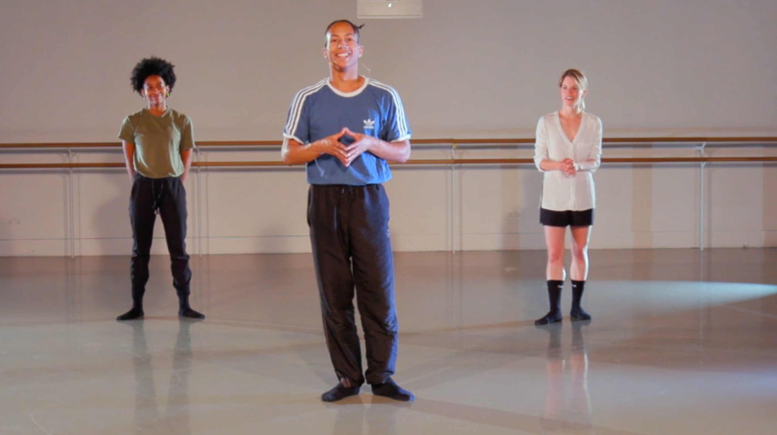 Teacher, a black man with a blue t-shirt, and two students behind him within the studio.