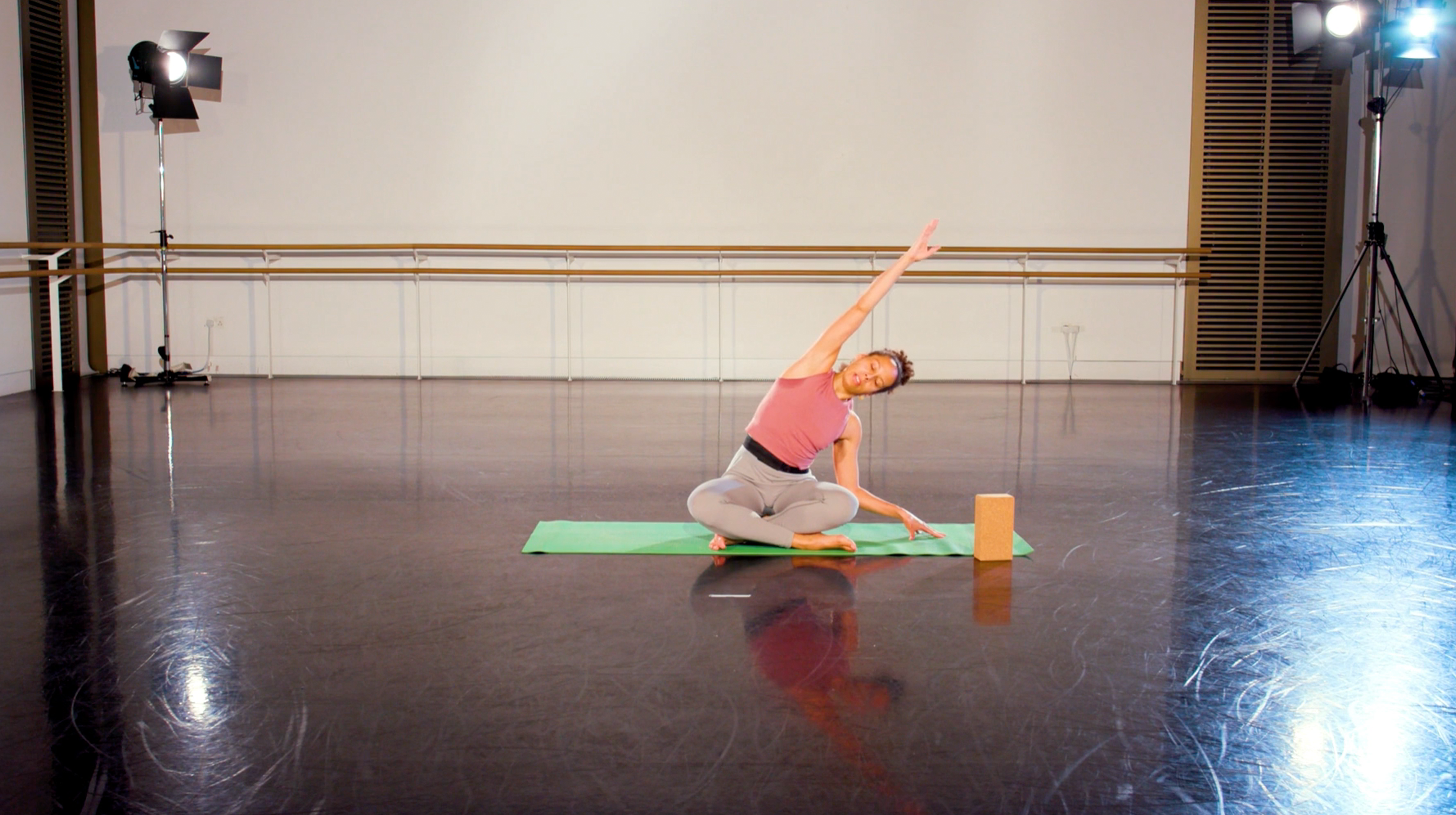 Teacher with a pink shirt in a yoga pose in the middle of a class