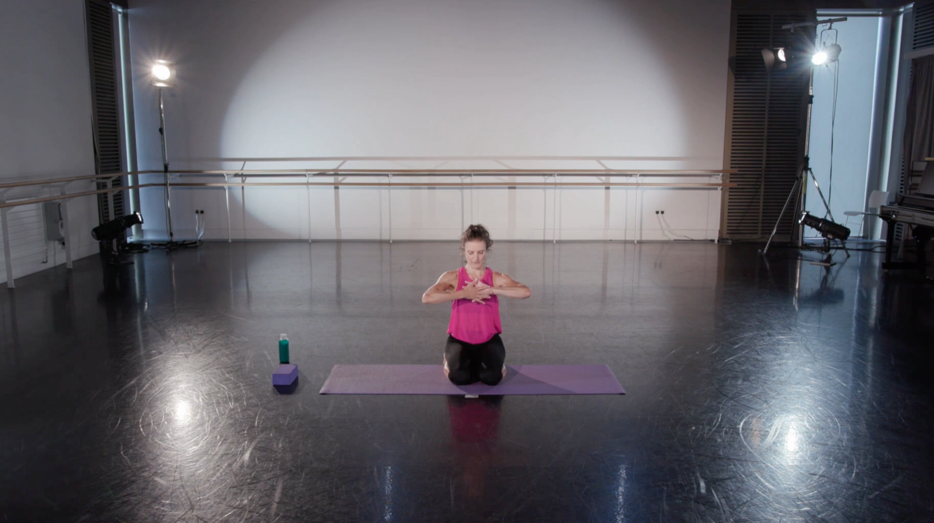 Teacher in a pink shirt sat in a studio getting ready to start an online class