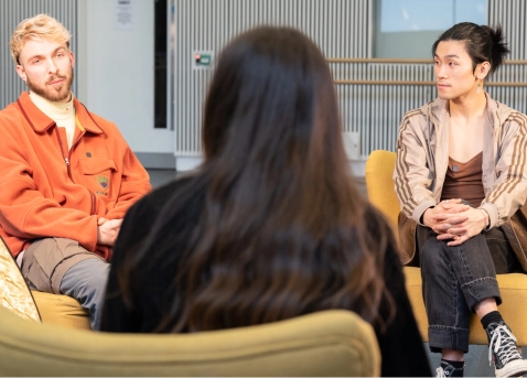 Three people sitting in a semi-circle having a discussion in a brightly lit room with modern decor.