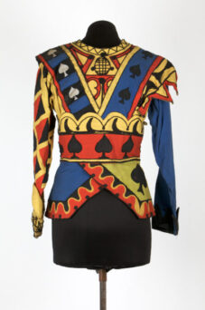 Colorful costume with playing card suit motifs, geometric patterns in red, yellow, blue, and black, displayed on a mannequin against a plain background.